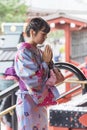 Young woman in kimono praying at the SensÃÂ-ji Buddhist temple A